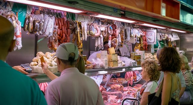 Malaga, Spain - August 04, 2018. Spanish prosciutto or jamon iberico and other Spanish specialities at the market of Ataranzanas Central Market, Malaga, Spain