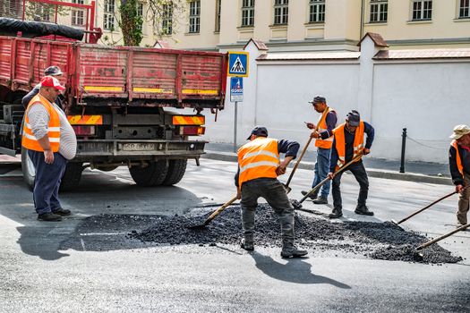 Sibiu City, Romania - 02 May 2019. Workers repair broken asphalt road in Sibiu city, Romania