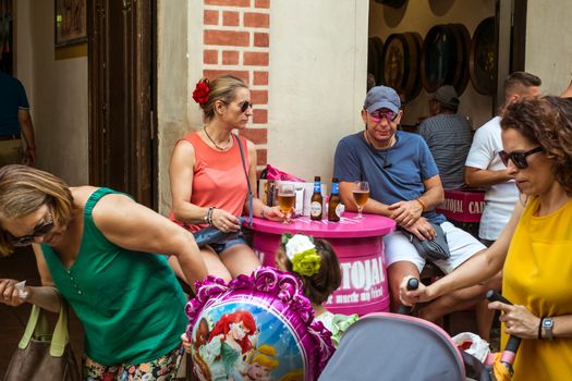 Malaga, Spain - August 12, 2018. A couple of tourists enjoy a beer at the table of a restaurant in the old center of Malaga city, Spain