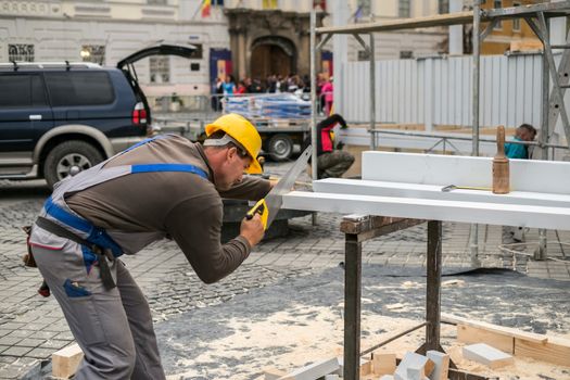 Sibiu, Romania - September 29, 2018. Worker cutting a beam for construction with a saw in a grand square, Sibiu, Romania