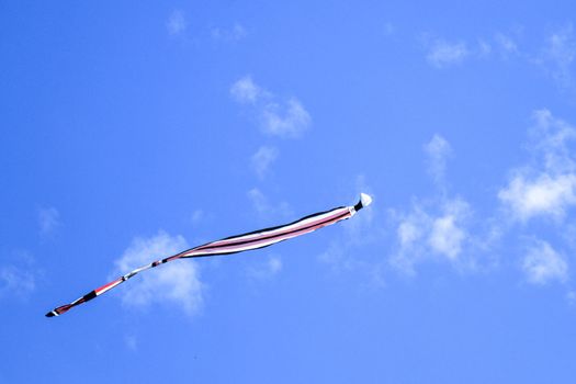 kite long tailfly on blue sky. The colorful kite on the blue sky with clouds. Space for text.