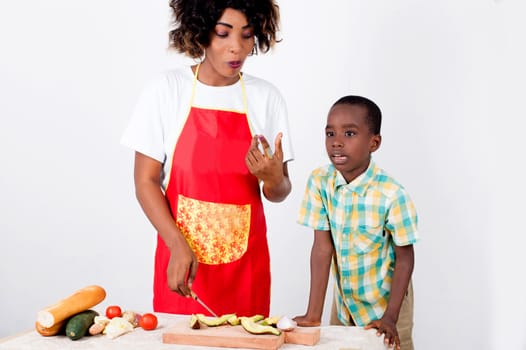 Young woman and her child preparing a meal with avocado, tomato bread and cucumber