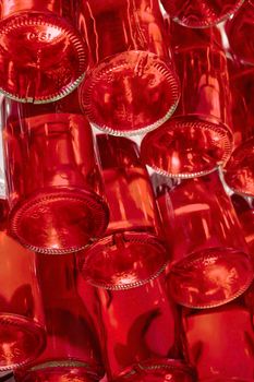 Wine bottles stacked in drink store. Many stacked glass bottles with volume of 0.5 liters of red color. Red bottles bottom. Abstract background. Background of bottles with red liquid Beverage industry