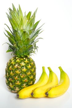A whole pineapple and three bananas against a plain white background