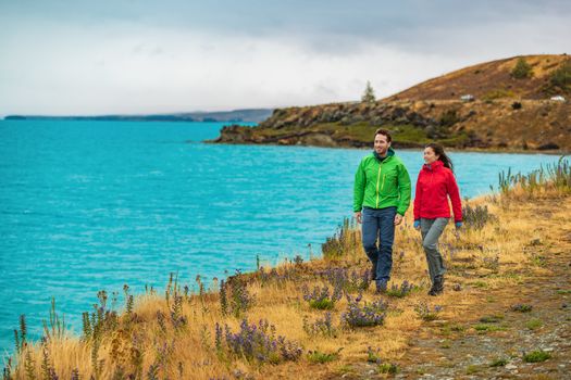 Active people in outdoor activity. Couple tourists hiking in nature with view of Lake Pukaki near Aoraki aka Mount Cook, a famous tourist destination on New Zealand.