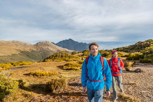 Young hiking couple walking at Routeburn Track during sunny day. Hikers are carrying backpacks while tramping on Key Summit Track. They are on vacation at Fiordland National Park in New Zealand.