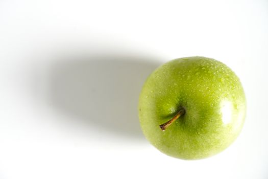 A whole granny smith green apple against a plain whit background