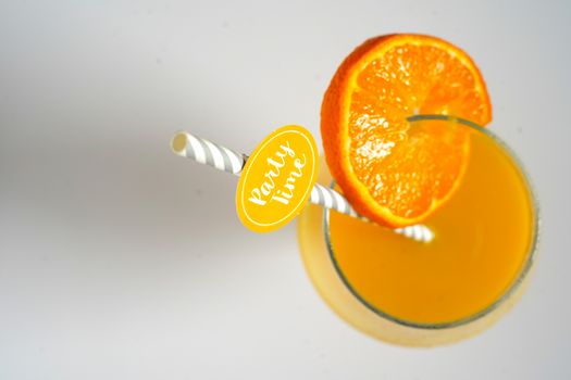 An orange cocktail drink with a party straw against a plain white background