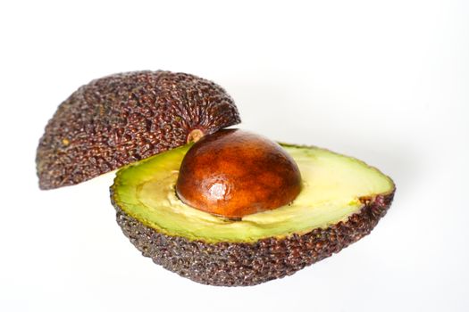 An avocado sliced in half to reveal the core against a plain whit background