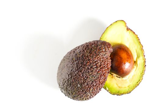 An avocado sliced in half to reveal the core against a plain whit background