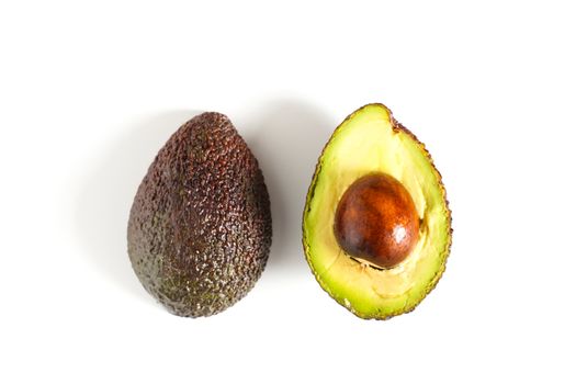 An avocado sliced in half to reveal the core against a plain whit background