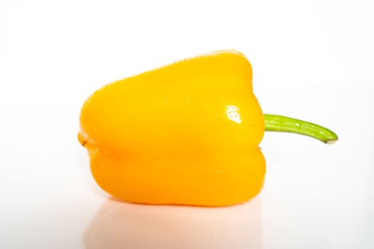 A whole yellow pepper against a plain whit background