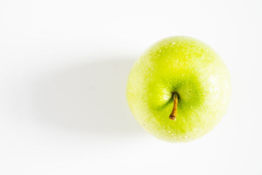 A whole granny smith green apple against a plain whit background