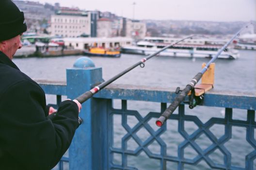 Istanbul, Turkey - February 24, 2007: Fishermen and urban scene, at the Galata Bridge, Istanbul, Turkey