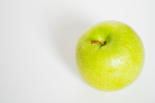 A whole granny smith green apple against a plain whit background