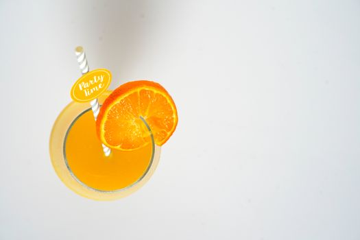 An orange cocktail drink with a party straw against a plain white background