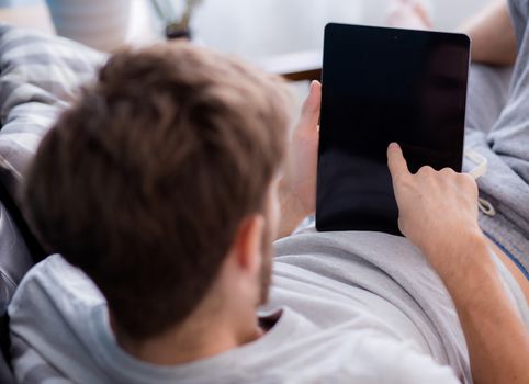 Happy man watching media content in a tablet sitting on a couch at home, Top side view mock up background