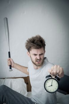 Portrait upset angry with baseball hit young man screaming at alarm clock on bedroom. Employee running late. Time management with business concept