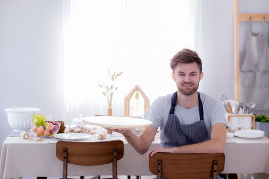 Man chef smiling looking camera with holding tray empty kitchen background