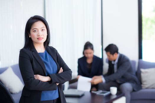 Beautiful woman standing with arms folded with colleagues in team on background.