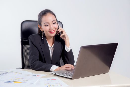 Young businesswoman working in office, typing, using computer and talking phone - Concentrated woman searching information online.