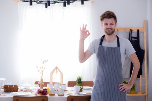 portrait of a smiling male cook gesturing okay sign in the kitchen