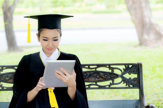 Graduate playing tablet in her hand feeling relaxing and so happiness in commencement day and search job new