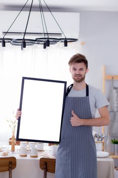 handsome chef showing blank empty board menu sign for restaurant menu or recipe with food table background.