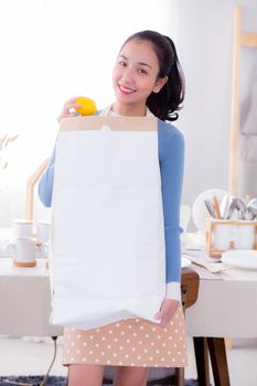 Portrait of a woman holding a paper bag with groceries.
