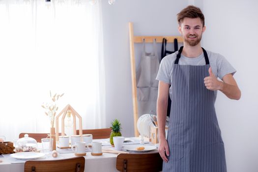 portrait of a smiling male cook gesturing visit sign in the kitchen.
