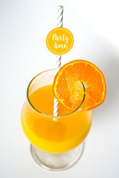 An orange cocktail drink with a party straw against a plain white background