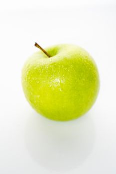 A whole granny smith green apple against a plain whit background