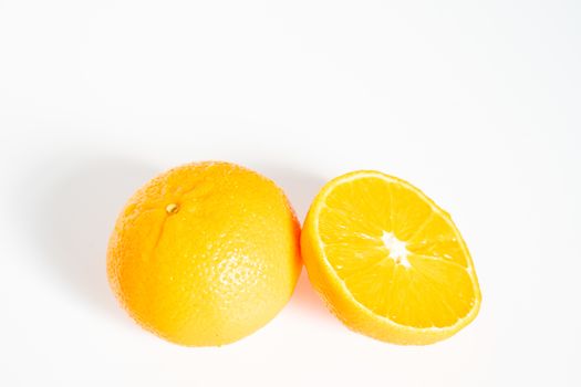 A whole orange and a half against a plain white background