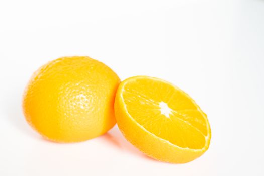 A whole orange and a half against a plain white background