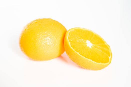 A whole orange and a half against a plain white background