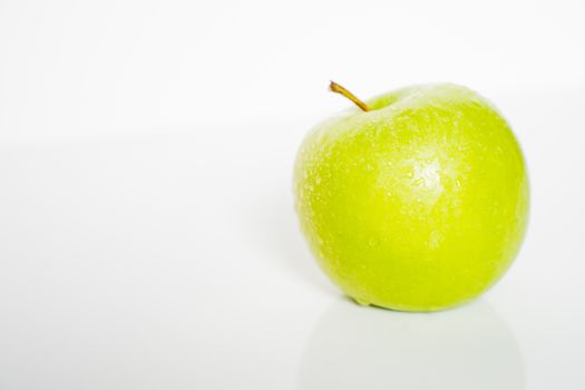 A whole granny smith green apple against a plain whit background