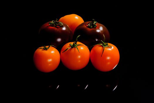 Light and dark tomatoes on a black surface
