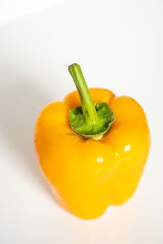 A whole yellow pepper against a plain whit background