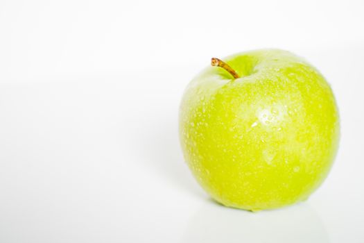 A whole granny smith green apple against a plain whit background