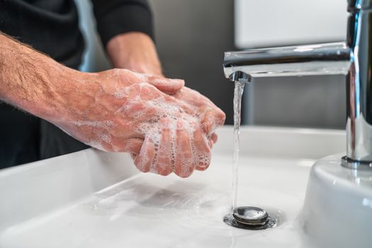 Corona virus travel prevention man showing hand hygiene washing hands with soap in hot water for coronavirus germs spreading protection.