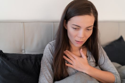 Coronavirus disease (COVID-19) Corona virus illness can be more severe for some people and can lead to pneumonia or breathing difficulties. Asian woman with shortness of breath sick at home.