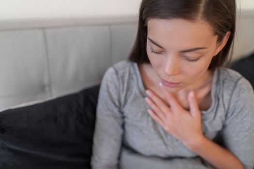 Coronavirus (COVID-19) Corona virus infectious disease symptoms include shortness of breath, chest pain. For some people and can lead to pneumonia or breathing difficulties. Asian woman sick at home.