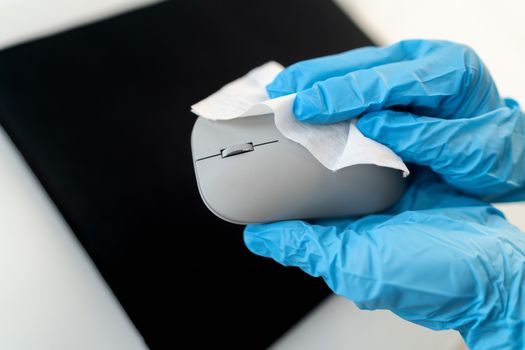 Office sanitizing wipe wiping mouse and mousepad with disinfecting wipes. Coronavirus COVID-19 sanitize cleaning disinfection of work desk. Antibacterial wipe the surfaces against corona virus.