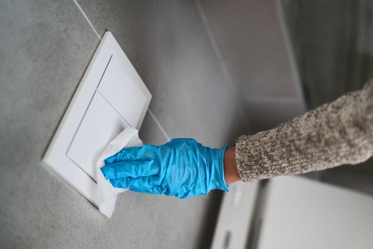Surface sanitizing wipes of bathroom surfaces, toilet flush wall button wiping paper towel sanitizer with gloves.