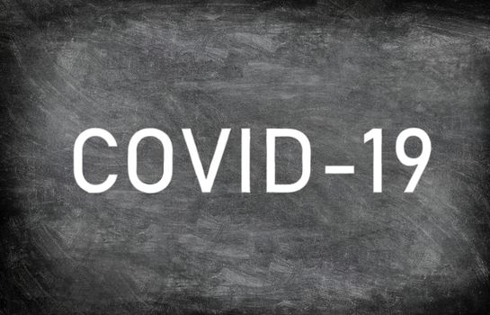 COVID-19 white chalck text on blackboard chalkboard texture distressed grunge background. Graphic design of corona virus drawing with title.