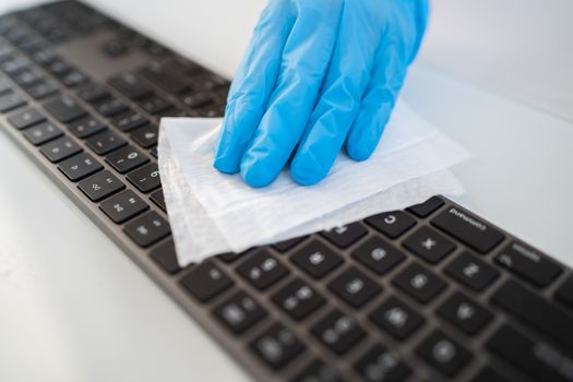 Covid-19 sanitizing office space wiping corona virus cleaning and disinfection of your workspace. Disinfecting wipes to wipe surface of desk, keyboard, mouse at office. Stop the spread of coronavirus.