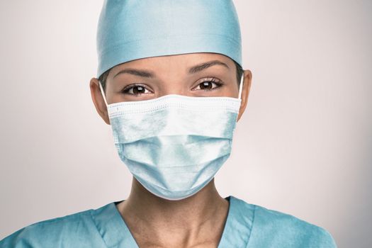 COVID-19 Coronavirus pandemic happy Asian doctor positive with hope wearing surgical mask and blue protective scrubs at hospital. Inspiring confidence in the future to solve the crisis.
