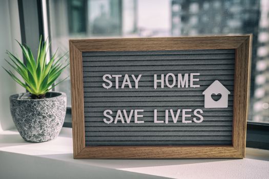 STAY HOME SAVE LIVES staying home self quarantine COVID-19 Coronavirus text message sign for social distancing awareness. COVID-19 staying at home window background. Flatten the curve.