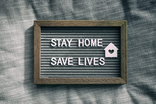 COVID-19 text for self isolation staying at home . Stay home, save lives. Coronavirus quote sboard sign with message of self quarantine for social responsability on home background.
