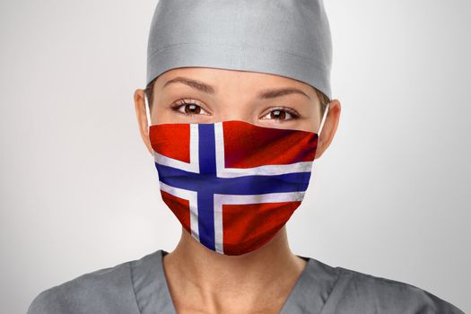 Norway COVID-19 doctor woman wearing PPE protective face mask with Norwegian flag for coronavirus prevention. Asian nurse happy. Health care worker helping.